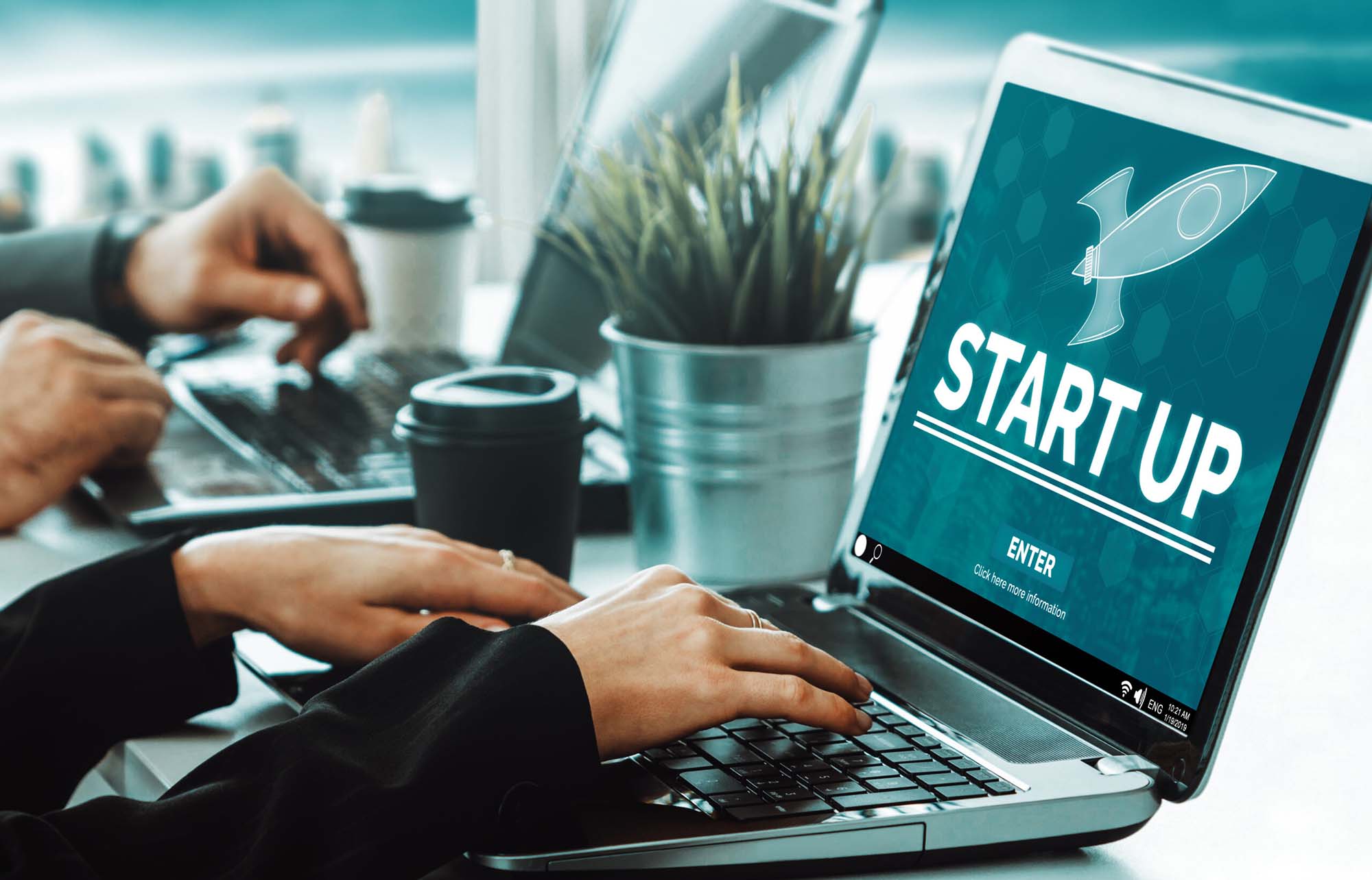 Nahaufnahme von zwei Gründern, die auf ihren Laptops arbeiten.